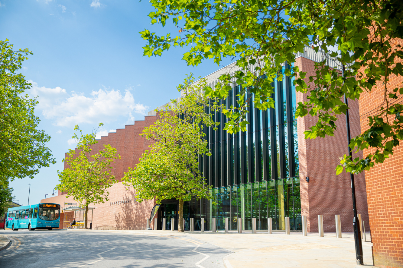 An exterior photo of Shakespeare North Playhouse, taken on a sunny day, with green trees in the foreground An exterior photo of Shakespeare North Playhouse, taken on a sunny day, with green trees in the foreground