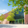 An exterior photo of Shakespeare North Playhouse, taken on a sunny day, with green trees in the foreground